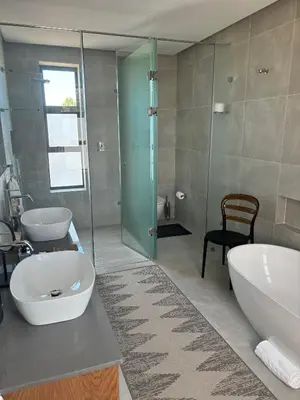 a bathroom with two sinks and a tub and a glass shower at Vergenoegd Löw Boutique Hotel & Spa in Somerset West
