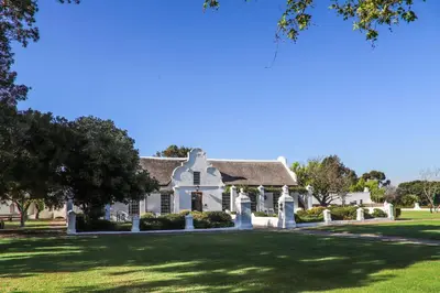 a large white house with a green lawn at Vergenoegd Löw Boutique Hotel & Spa in Somerset West