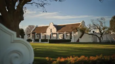 a large white house with a grass yard at Vergenoegd Löw Boutique Hotel & Spa in Somerset West