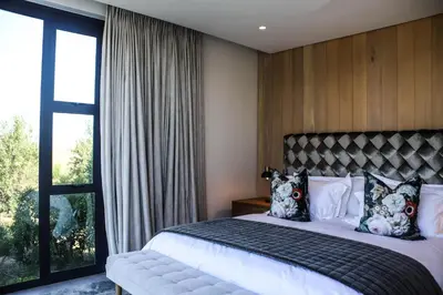 a bedroom with a bed and a large window at Vergenoegd Löw Boutique Hotel & Spa in Somerset West