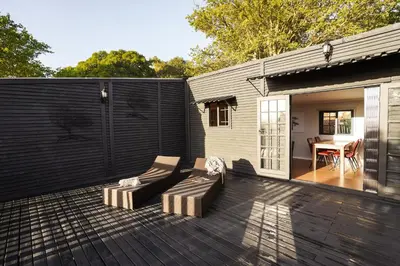 a patio with a couch and a table on a deck at Avemore Vineyard View - wood fired hot tub and full power back up in Onder-Papegaaiberg