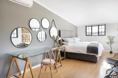 a bedroom with a bed and a table and mirrors at Avemore Vineyard View - wood fired hot tub and full power back up in Onder-Papegaaiberg