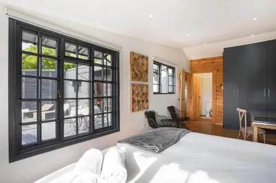 a bedroom with a bed and a large window at Avemore Vineyard View - wood fired hot tub and full power back up in Onder-Papegaaiberg