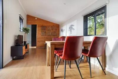 a dining room with a wooden table and red chairs at Avemore Vineyard View - wood fired hot tub and full power back up in Onder-Papegaaiberg