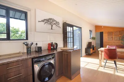 a kitchen with a washer and dryer in a room at Avemore Vineyard View - wood fired hot tub and full power back up in Onder-Papegaaiberg