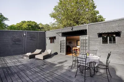 a patio with a table and chairs and a building at Avemore Vineyard View - wood fired hot tub and full power back up in Onder-Papegaaiberg