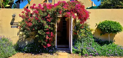 a building with a bunch of flowers on it at SAGE Cottage Bloubergstrand in Cape Town