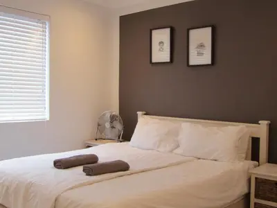 a bedroom with a white bed with two pictures on the wall at Surfhostel Cape Town in Cape Town