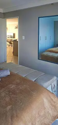a room with two beds and a mirror on the wall at OCEAN VIEW, Blouberg Beach, Sunsets & Kite Beach in Bloubergstrand