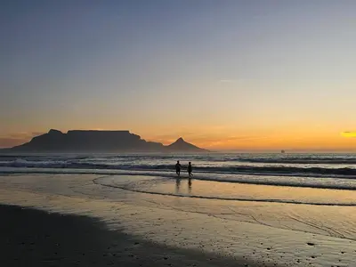 two people walking on the beach at sunset at OCEAN VIEW, Blouberg Beach, Sunsets & Kite Beach in Bloubergstrand