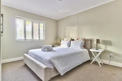 a white bedroom with a large white bed and a window at 2 Bedroom Apartment in Century City 204QS in Cape Town