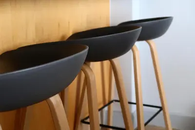 two black bar stools with wooden legs next to a wall at Beachfront Gem / Free Parking / A/C in Cape Town