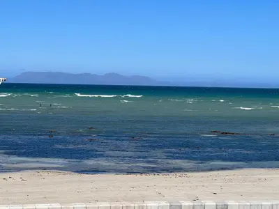 a beach with the ocean and people in the water at Beachfront Gem / Free Parking / A/C in Cape Town