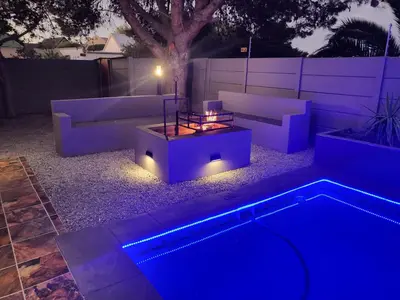 a backyard with a couch and a pool at night at Willow Retreat Blouberg in Cape Town