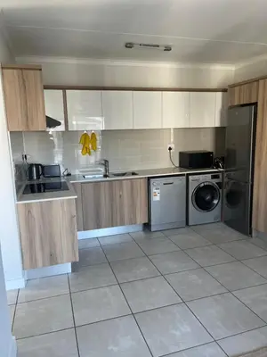 a kitchen with white cabinets and a washer and dryer at Casa The Jade in Cape Town