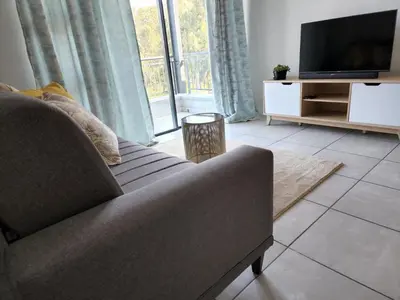 a living room with a couch and a flat screen tv at Casa The Jade in Cape Town
