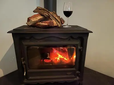 a fireplace with a glass of red wine and a glass of wine at Bing Heights Suite in Hermanus