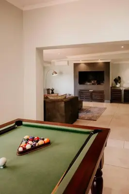 a living room with a pool table and a room with a tub at Villa Visser in Cape Town