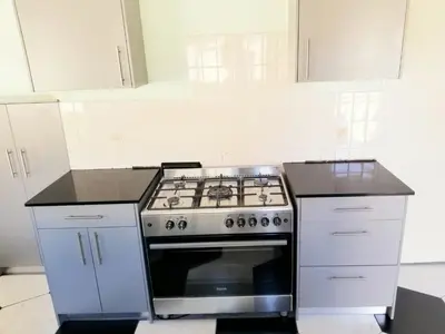 a kitchen with a stove and white cabinets at Capetown Adilo Villa in Cape Town
