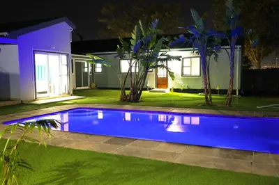 a swimming pool in front of a house at night at El-Gibor Best Guest House in Cape Town