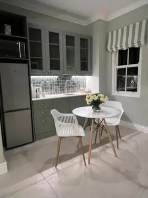 a kitchen with a table and two chairs and a table with flowers at Two on Milner - OAK TREE COTTAGE - Stylish open-plan Guesthouse in Rondebosch in Cape Town