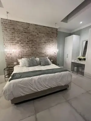 a bedroom with a large bed with a brick wall at Two on Milner - ARUM COTTAGE - Stylish open-plan Guesthouse in Rondebosch in Cape Town