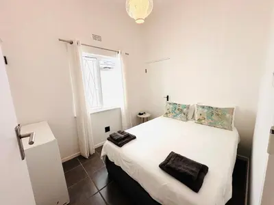 a bedroom with a bed with white sheets and a window at 2-Bedroom Hermanus - Sleeps 4 - Near Sea in Hermanus