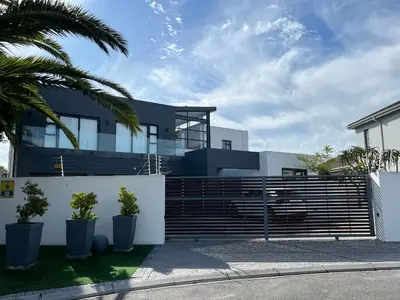 a house with a fence and palm trees at Cowrie Cottage Self Catering in Cape Town