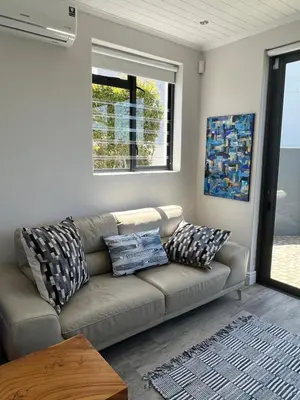 a living room with a couch and a window at Cowrie Cottage Self Catering in Cape Town