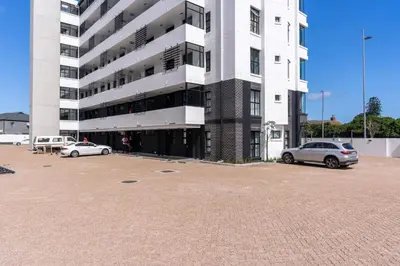 a large white building with cars parked in a parking lot at Burmeister 401 - 2 Bedroom Apartment across from Ocean - Onsite Parking in Cape Town