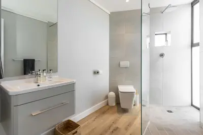 a white bathroom with a sink and a shower at Burmeister 401 - 2 Bedroom Apartment across from Ocean - Onsite Parking in Cape Town