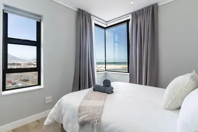 a bedroom with a bed with a teddy bear on it at Burmeister 401 - 2 Bedroom Apartment across from Ocean - Onsite Parking in Cape Town
