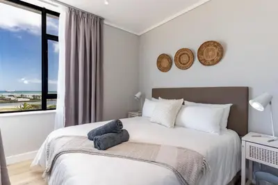 a bedroom with a bed and a large window at Burmeister 401 - 2 Bedroom Apartment across from Ocean - Onsite Parking in Cape Town