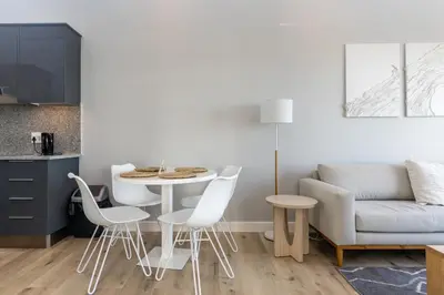a living room with a table and chairs and a couch at Burmeister 607 - Top Floor Corner 2 Bedroom Apartment with Sea and Lagoon Views - Onsite Parking in Cape Town