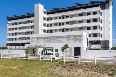 a white building with a car parked in front of it at Burmeister 607 - Top Floor Corner 2 Bedroom Apartment with Sea and Lagoon Views - Onsite Parking in Cape Town