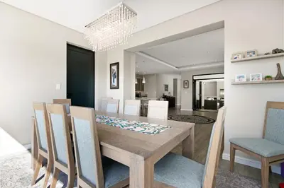 a dining room with a wooden table and chairs at On the Greens Villa in Cape Town