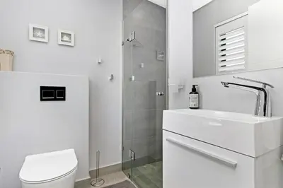 a bathroom with a toilet and a sink and a shower at On the Greens Villa in Cape Town