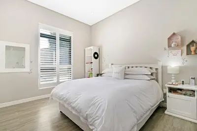 a white bedroom with a white bed and a window at On the Greens Villa in Cape Town