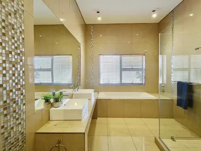 a bathroom with a sink and a tub and a mirror at Kite, Wind, Waves Beach Villa in Cape Town