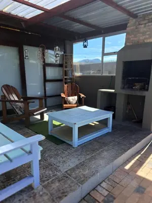 a patio with a white table and a fireplace at 68 On Hofmeyr in Strand