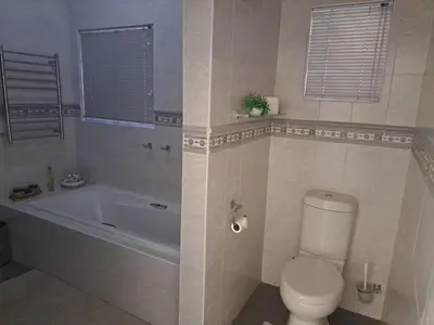 a bathroom with a tub and a toilet and a sink at 68 On Hofmeyr in Strand