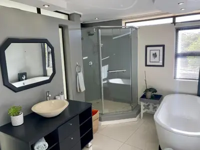 a bathroom with a sink and a glass shower at Rose’s Place in Durbanville