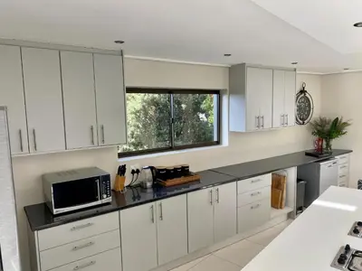 a kitchen with white cabinets and a microwave at Rose’s Place in Durbanville