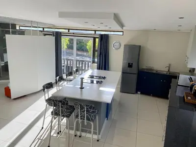a kitchen with a sink and a counter with stools at Rose’s Place in Durbanville