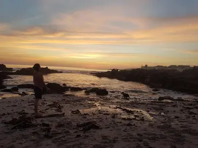 a person standing on a beach with the ocean at Mountain and Sea Cottage in Hermanus