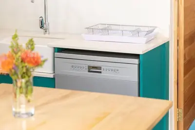 a kitchen counter with a dishwasher and a table at Mountain and Sea Cottage in Hermanus