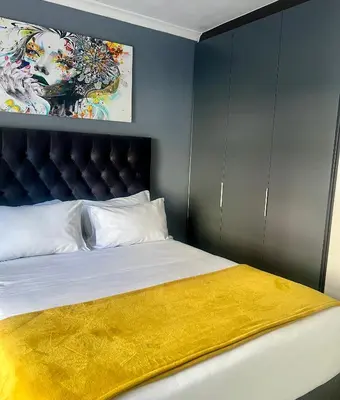 a bedroom with a bed with a yellow blanket on it at The CoziPlace Italia in Cape Town