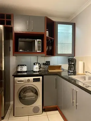 a kitchen with a washing machine and a microwave at The CoziPlace Italia in Cape Town