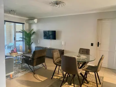 a dining room and living room with a table and chairs at The CoziPlace Italia in Cape Town