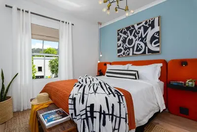 a bedroom with an orange and white bed and a window at The Tram Stop in Franschhoek